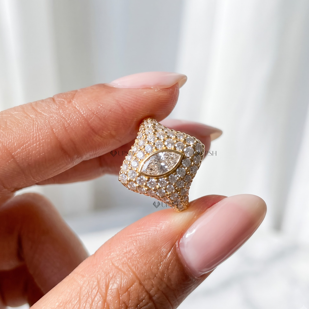 Close-up shot holding yellow gold marquise bezel diamond pave pinky ring.