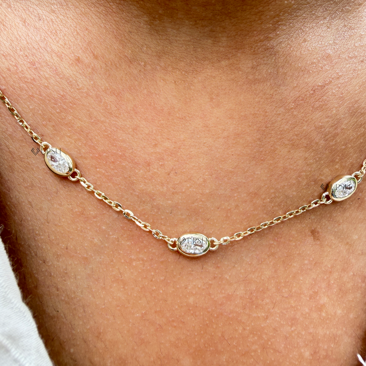 Detailed macro view of yellow gold bezel set oval diamond station resting against collarbone