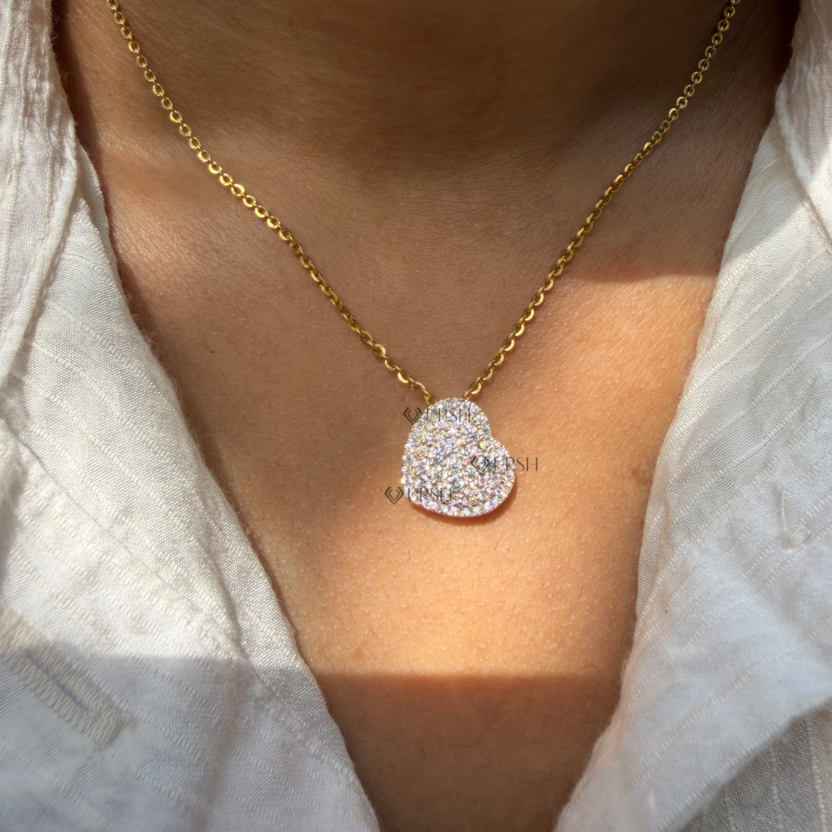 Daylight perspective view of yellow gold diamond heart cluster pendant resting along collarbone