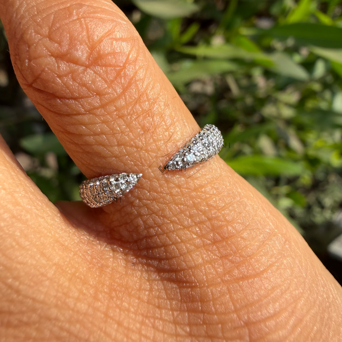 Detailed daylight macro close-up of micro-pavé set tapered terminals and open gap detail worn on finger