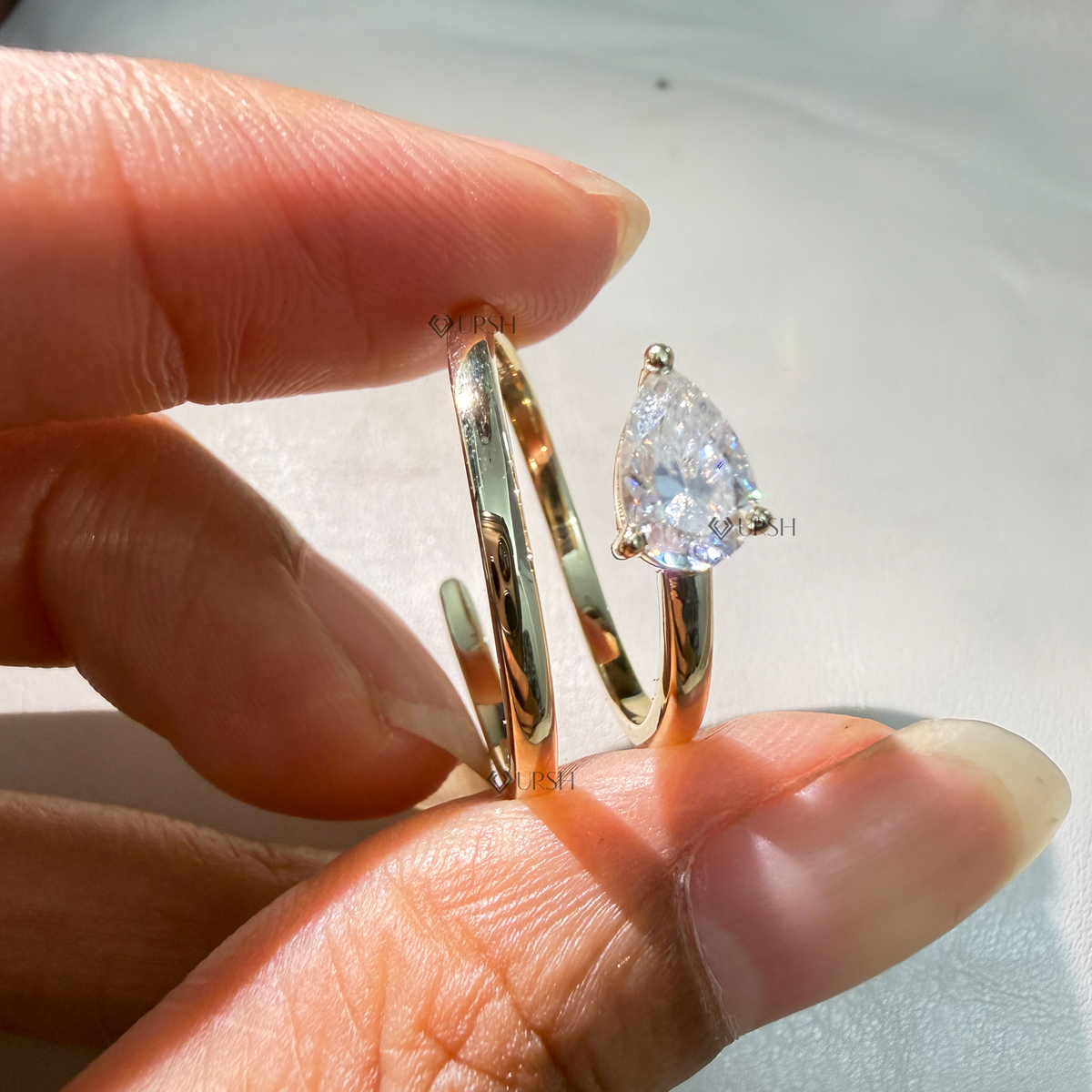 Close-up daylight angle view of yellow gold spiral ring worn on finger displaying wrap coil flow