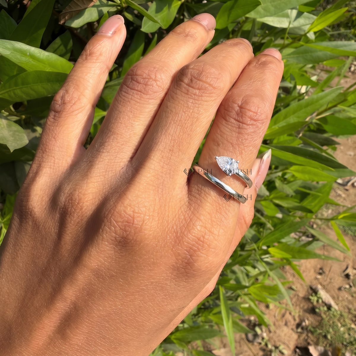 Solid white gold pear-cut diamond spiral bypass wrap ring worn gracefully on hand in natural daylight