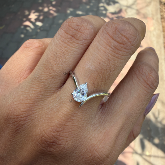 Teardrop pear cut lab diamond curved chevron ring worn on finger in natural daylight