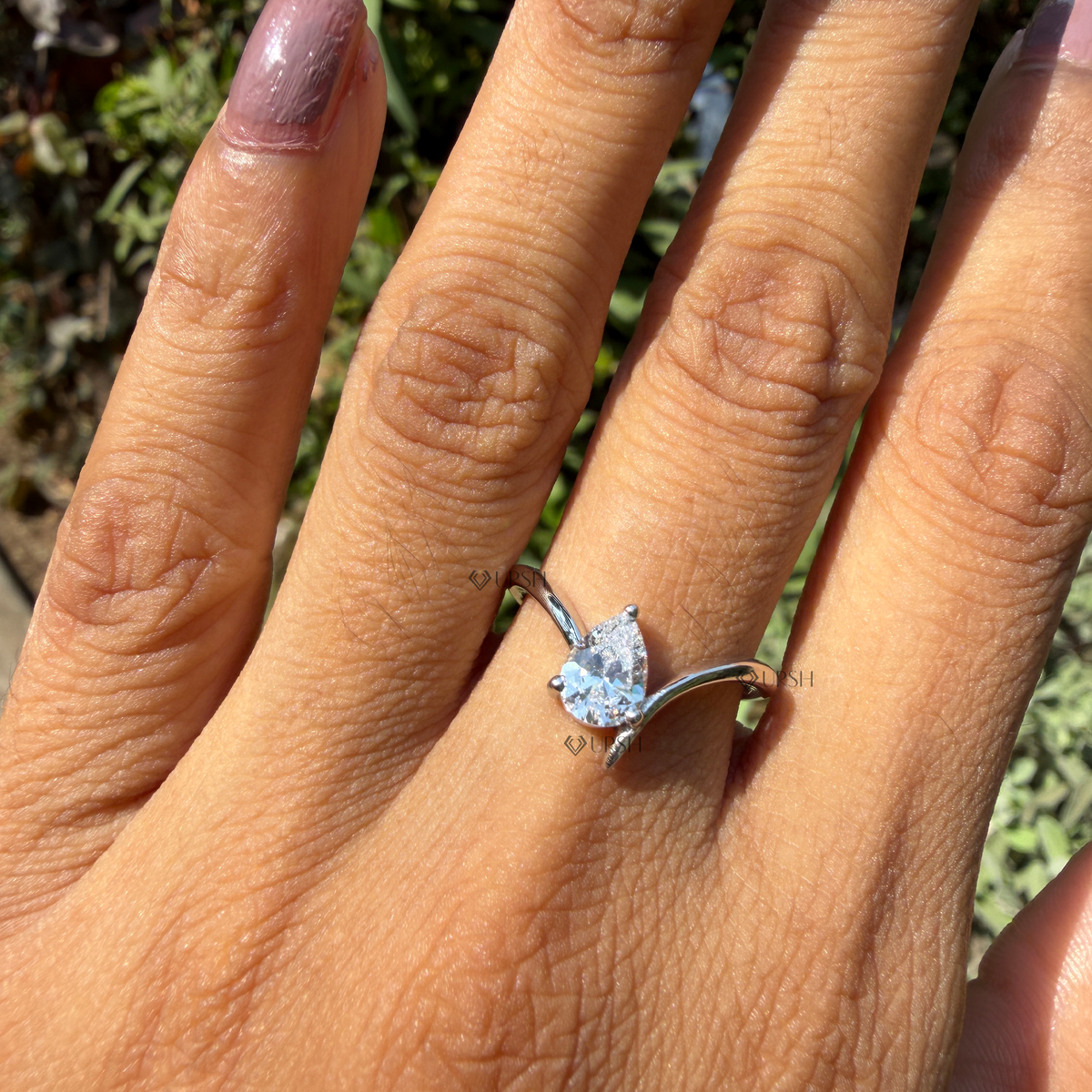 Pear cut lab grown diamond asymmetrical contour band catching sunlight on ring finger