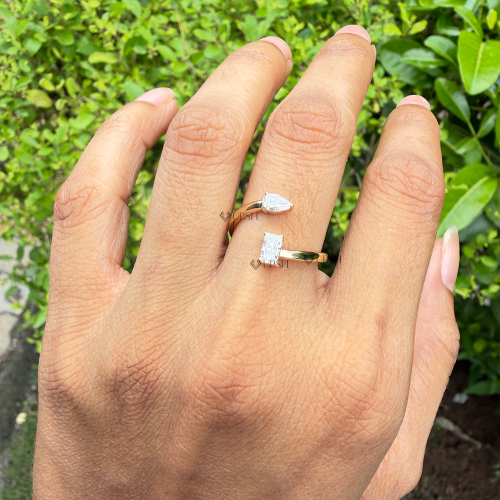 Radiant and pear diamond bypass statement ring styled on hand with green foliage backdrop