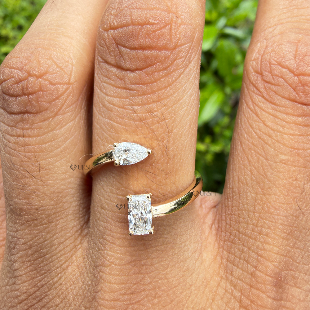 Two-stone radiant and pear diamond open bypass ring worn on finger in natural daylight