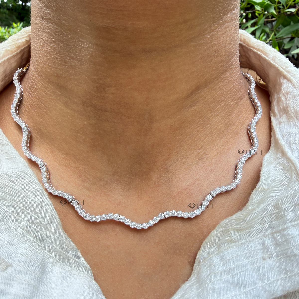 Daylight angle view of white gold wavy diamond tennis chain necklace worn on neck