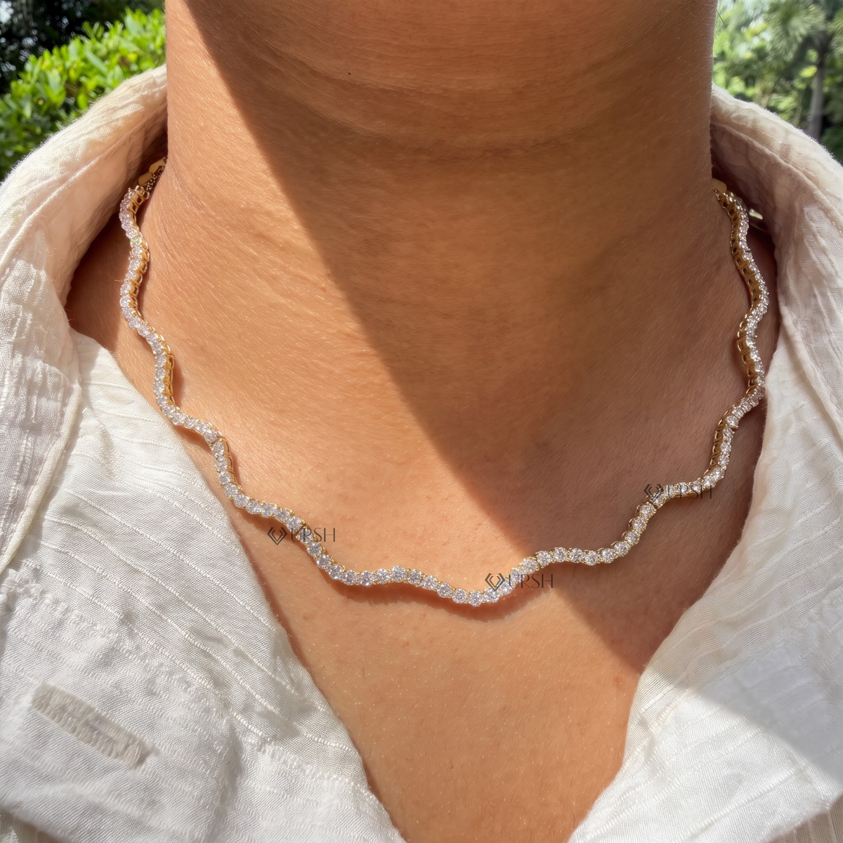 Yellow gold wavy diamond tennis chain necklace styled gracefully on neck in natural daylight